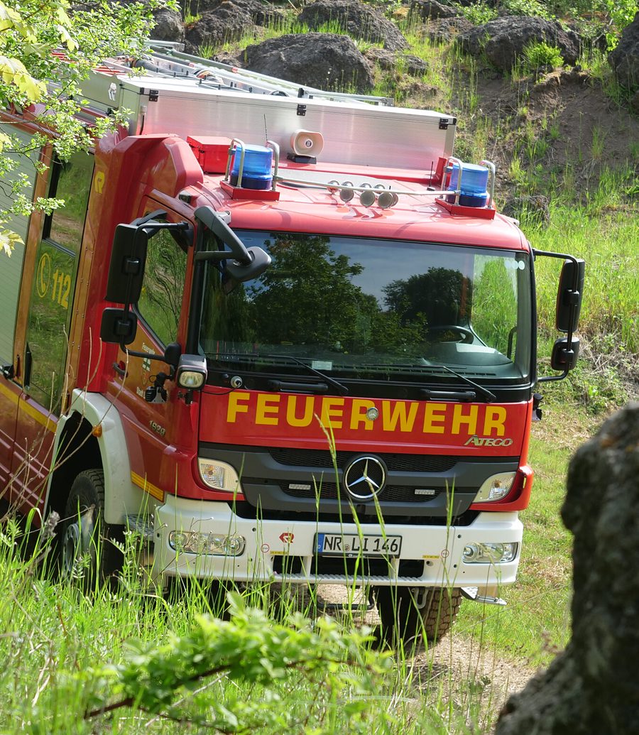 Allradgetriebener Feuerwehr-LKW im bewachsenen Gelände zwischen Felsen