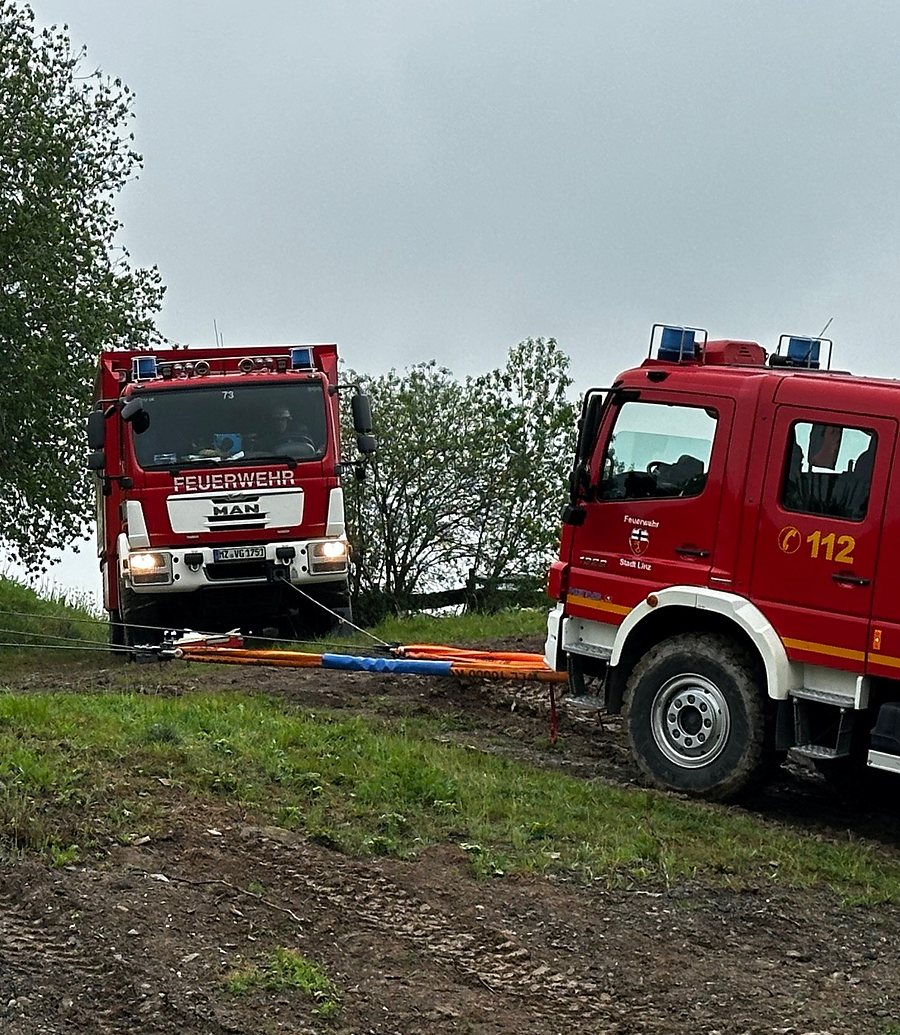 Feuerwehrfahrzeug am Hang, gehalten von gespannten Seilwindenseilen mit Bodenankern