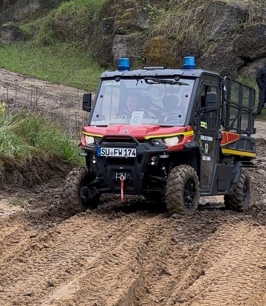 Feuerwehr-UTV mit Blaulicht fährt durch tiefen Schlamm
